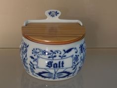 a blue and white jar with wooden lid on a counter top next to a wall