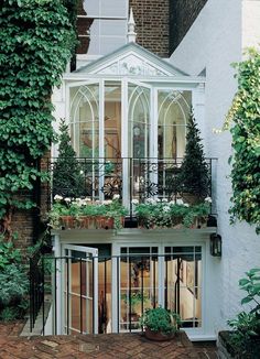 a white house with lots of windows and plants on the balconies