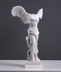 a white statue with wings on top of a table