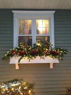 a window sill with christmas lights and greenery on the windowsill in front of a house