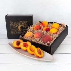 a box of sliced peaches on a plate next to a black box with gold foil