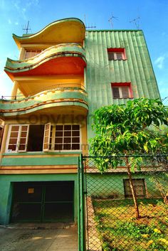 a tall building with a green and yellow roof next to a fenced in area