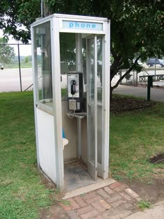 an old phone booth sitting in the grass