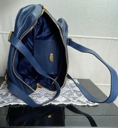 Beautiful Miu Miu handbag in a wonderfully intense shade of blue. An absolute miracle of space. Dimensions : 33cm x 21cm x 15cm. Shiny gold hardware and massive zipper with Miu Miu engraving. Two side pockets inside, one with a zip, the other as a sturdy leather compartment. The bag is fully lined with shiny tone on tone lining. The handles can be adjusted in length. The dimension is a maximum of 70 cm. The bag has the style of a bowling bag and is absolutely practical and easy to carry. Extrava Luxury Navy Shoulder Bag For Everyday Use, Blue Satchel With Top Carry Handle For Evening, Elegant Navy Satchel With Detachable Strap, Modern Blue Handheld Shoulder Bag, Elegant Navy Satchel With Spacious Interior, Luxury Blue Shoulder Bag For Everyday Use, Blue Satchel With Removable Pouch For Evening, Modern Handheld Blue Shoulder Bag, Elegant Navy Shoulder Bag With Top Carry Handle