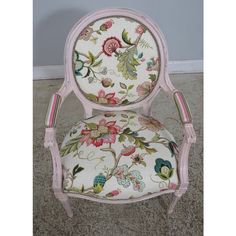 a pink chair with floral upholstered fabric on it's back and arms