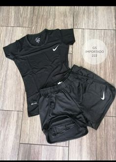 a black shirt and shorts are on the floor next to a pair of nike shoes