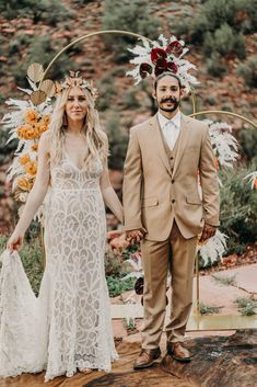 a bride and groom holding hands while standing in front of an arch decorated with flowers