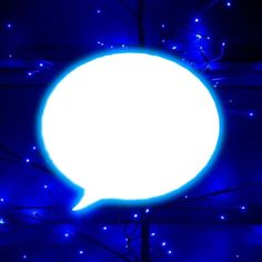 a large white speech bubble hanging from the side of a tree with blue lights around it