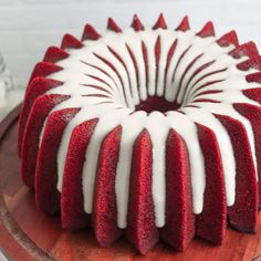 a red velvet bundt cake with white icing on a wooden platter, ready to be eaten