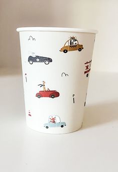 a paper cup with cars and trucks on the front is sitting on a white surface