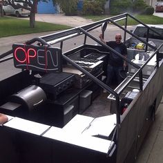 a man is standing in the back of a truck with an open grill on it