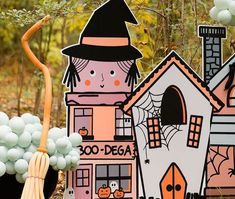 an outdoor halloween decoration with balloons and decorations on the ground, including a house shaped like a witch's hat