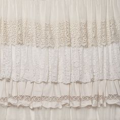 the curtain is white and has lace trim around it, along with ruffled edges