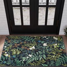 a door mat with flowers and leaves on it in front of a black double doors