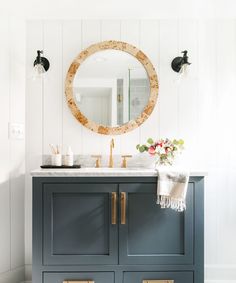 a bathroom vanity with two sinks and a round mirror on the wall above it,