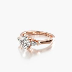 a rose gold ring with two pear shaped diamonds on the side, set against a white background