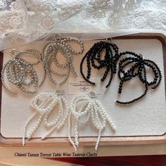 several necklaces are displayed in a box on a table with white lace and beads