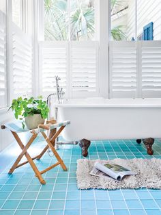 a white bath tub sitting next to a window with shutters on it's sides