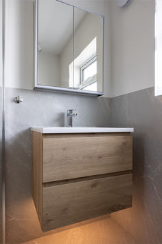 a bathroom vanity with a mirror above it and a light on the wall next to it