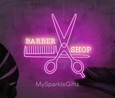 a neon sign that says barber shop with scissors and combs on it in front of a palm leaf