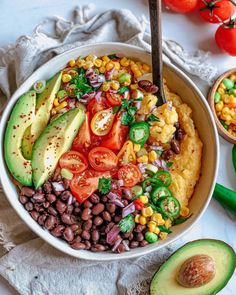 a bowl filled with beans, avocado, tomatoes and other veggies