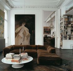 a living room filled with lots of furniture and books on top of a hard wood floor