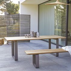 two wooden benches sitting next to each other on a cement floor near a building with sliding glass doors