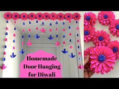 pink and blue paper flowers hanging from the ceiling with text that reads homemade door hanging for diwali