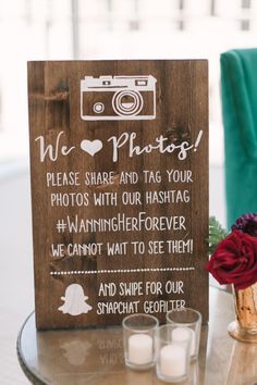 a wooden sign sitting on top of a glass table next to candles and a vase