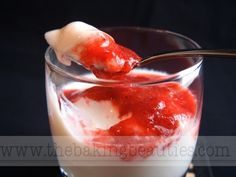 a spoon with some food in it on top of a glass filled with milk and strawberries