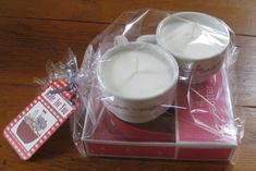 two white candles sitting on top of a red box next to a package of tissues