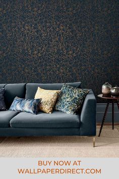 a blue couch sitting in front of a black wall with gold foiling on it