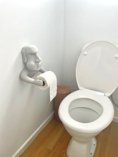 a white toilet sitting in a bathroom next to a roll of paper on the wall