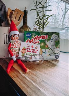 an elf is sitting on the counter next to some books and cooking utensils