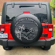 a black tire cover on the back of a red jeep