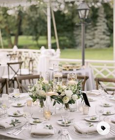 the table is set with white flowers, candles and place settings for an elegant dinner