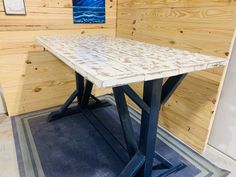 a wooden table sitting on top of a blue rug in front of wood paneled walls