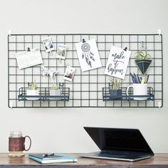 a laptop computer sitting on top of a wooden desk next to a wall mounted memo board