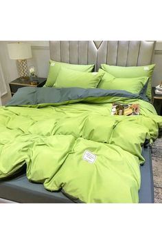 a bed covered in green sheets and pillows