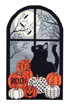 a black cat sitting on top of a window sill with pumpkins and bats