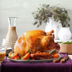 a roasted turkey on a platter with carrots and other vegetables next to it