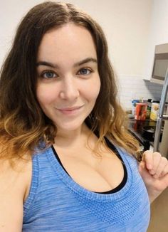 a woman in a blue tank top is posing for the camera