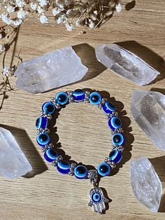 a bracelet with evil eye beads on it next to crystal stones and flowers in the background