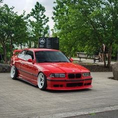 a red car parked in front of some trees