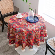 the table is covered with a red, orange and blue patterned tablecloth next to two chairs