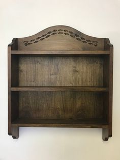 a wooden shelf with two shelves on each side and an intricately carved design at the top