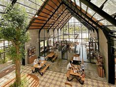 the inside of a building with tables and benches in front of windows that look out onto trees