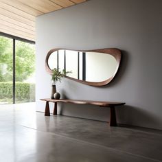 a wooden bench sitting next to a large mirror on the side of a white wall