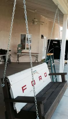 a white bucket sitting on top of a wooden swing in front of a building with windows