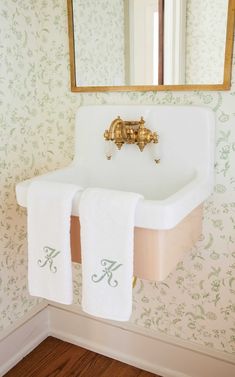 a bathroom sink with two white towels hanging from it's side and a mirror above it